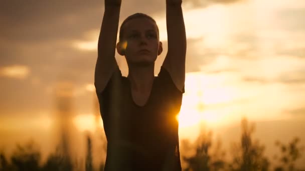 Vacker ung frisk kvinna gör yoga övning under solnedgången — Stockvideo