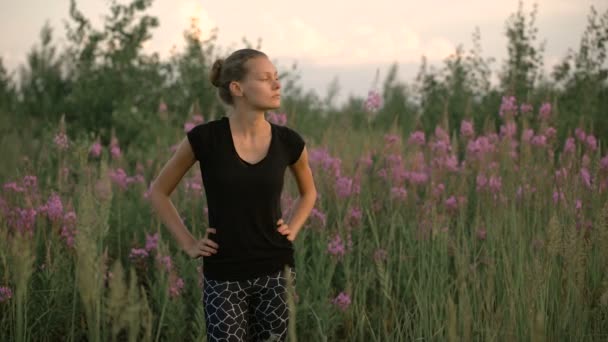 Mooie jonge gezonde vrouw staande op een groen veld en weg op zoek — Stockvideo
