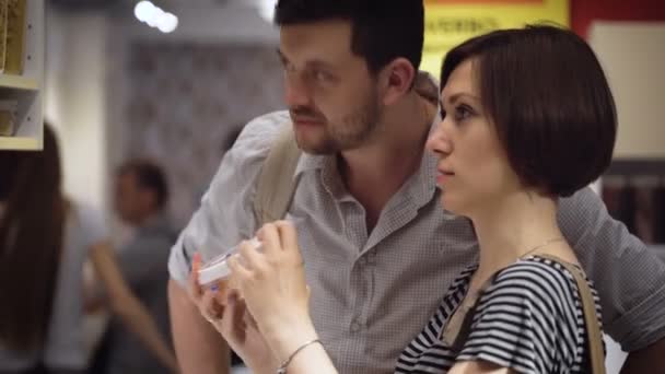 Hermosa pareja joven eligiendo cosas para la cocina en la tienda — Vídeo de stock