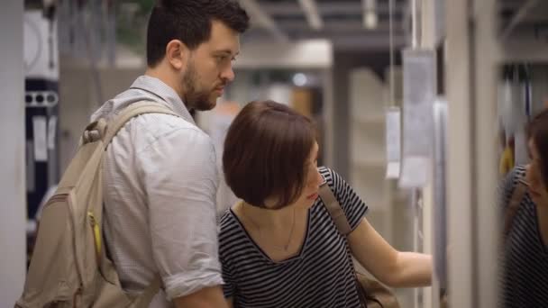 Schönes junges Paar wählt Kisten und Behälter im Geschäft — Stockvideo