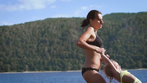 Madre jugando girando alrededor de su hija niña en el lago — Vídeos de Stock