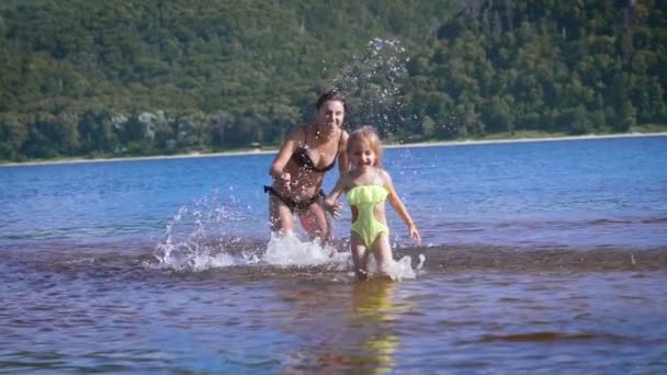 Madre jugando girando alrededor de su hija niña en el lago parque — Vídeo de stock