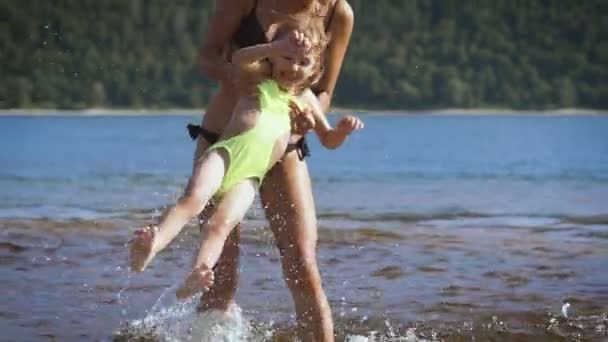 Mamma spelar vrida runt hennes bebis flicka dotter i parken sjön — Stockvideo