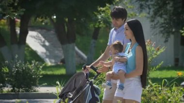 Genç aile Şehir Parkı kollarında küçük bir çocukla yürürken.