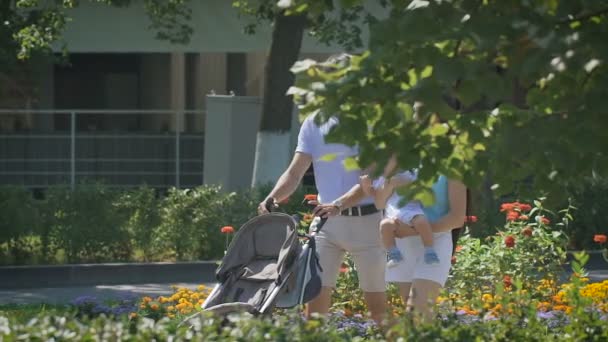 Ung familj gå på city park med en liten pojke i famnen. — Stockvideo