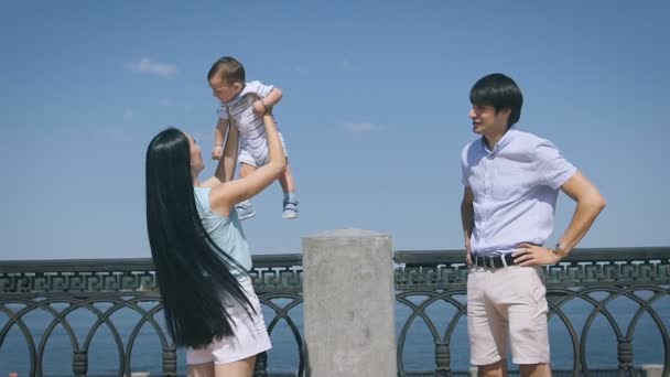 Happy family. Young mother throws up baby in the sky, on sunny day. — Stock Video