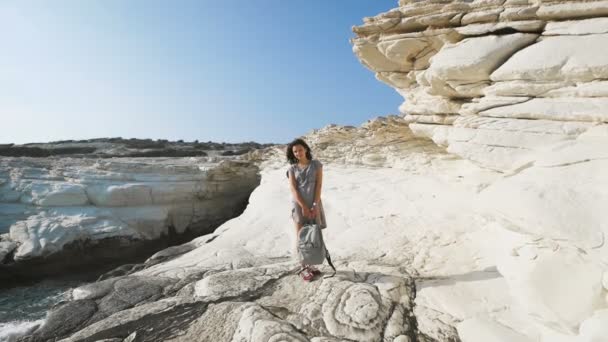 Una joven mujer de pie junto al mar en la camiseta larga — Vídeos de Stock