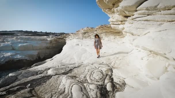 Uma jovem caminhando perto do mar com a camiseta comprida — Vídeo de Stock