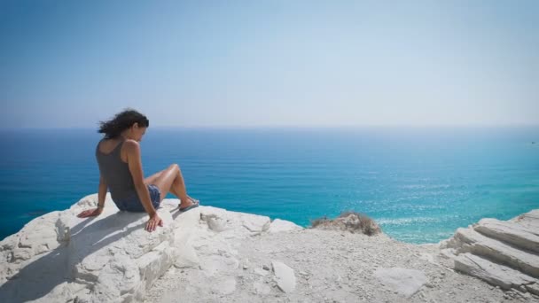 Una giovane donna seduta in riva al mare — Video Stock