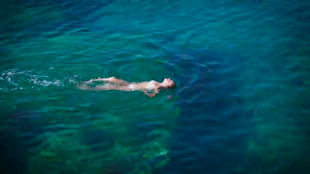 Νεαρή γυναίκα κολύμβησης στην όμορφη γαλάζια θάλασσα — Αρχείο Βίντεο