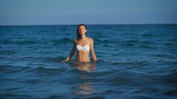 一个美丽的女人，在海中获得乐趣的白色比基尼 — 图库视频影像