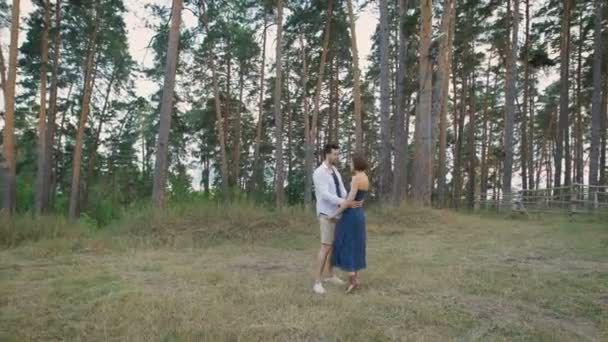 Schöne Männer und Frauen umarmen sich, wenn sie auf einer Lichtung inmitten eines Kiefernwaldes stehen. — Stockvideo