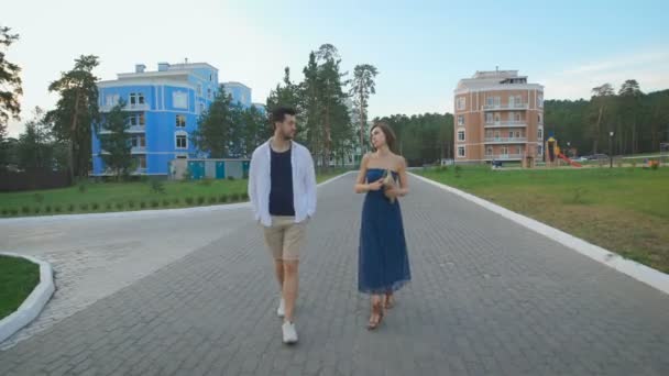 Bella coppia innamorati giovani tenendosi per mano e passeggiando sulla bella zona residenziale . — Video Stock