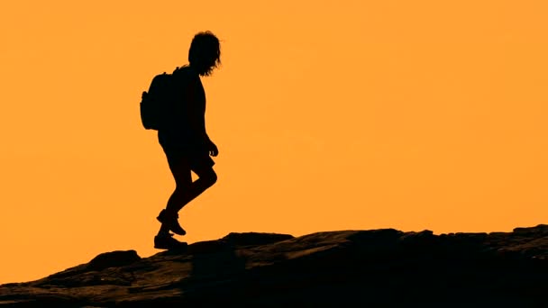 Silhueta de uma menina caminhando na montanha ao pôr do sol — Vídeo de Stock
