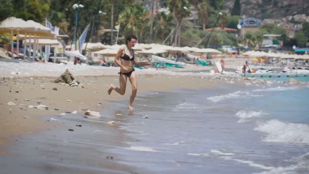 Eine junge schöne Frau, die am Meer rennt — Stockvideo