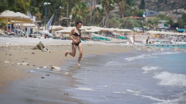 Une jeune belle femme courant sur une mer — Video