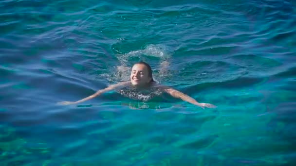 Eine junge glückliche Frau schwimmt im azurblauen Meer — Stockvideo