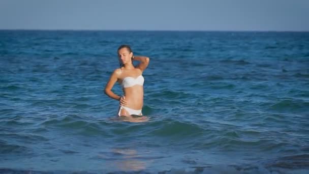 Een jonge mooie model draagt witte bikini genieten van zichzelf — Stockvideo