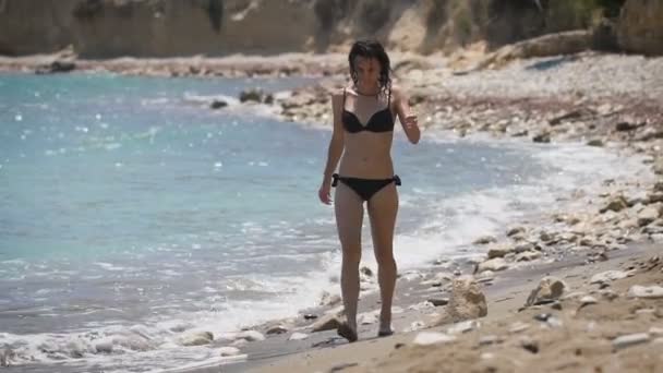 Vacaciones en playa. Hermosa mujer en bikini negro disfrutando de un día soleado perfecto caminando por la playa . — Vídeos de Stock