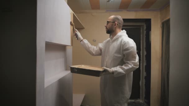 Pintor de casa con gafas y barba rodillo pinta la pared . — Vídeo de stock