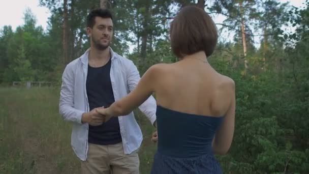 Un uomo piacevole con la barba conduce la sua bella moglie o ragazza su un sentiero nel bosco . — Video Stock