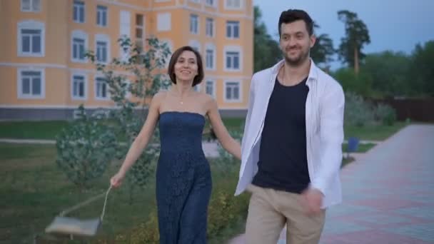 Šťastný pár novomanželů zábavu procházky po promenádě blízko jeho nového domova. — Stock video