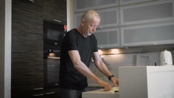 The man  preparing a meal in their modern kitchen. — Stock Video