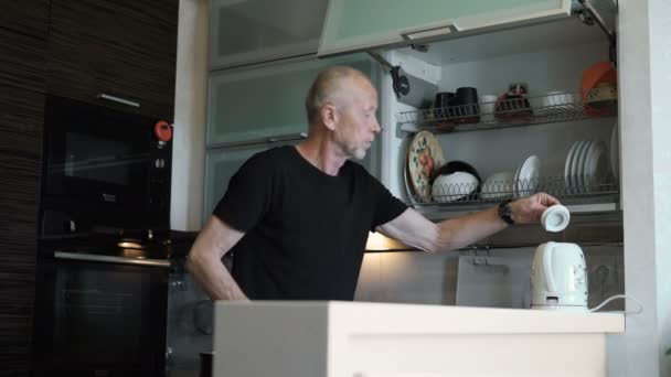 Um homem mais velho aposentado, passa tempo na cozinha de sua casa — Vídeo de Stock