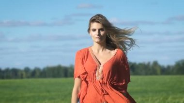 Yeşil alana seksi bir bakışla yavaşça yürüyen kırmızı gömlekli güzel sarışın genç romantik bir kadının yakın çekim portresi