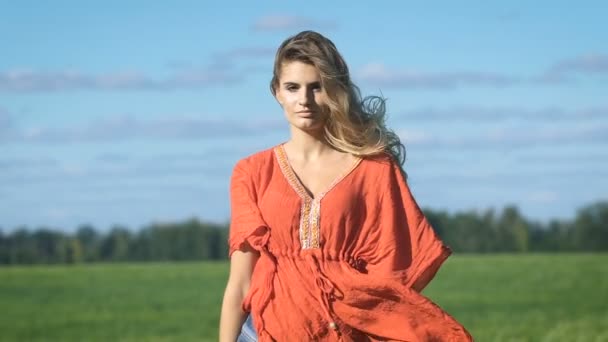 Крупним планом портрет красивої блондинки молодої романтичної жінки в червоній сорочці, що йде повільно з сексуальним поглядом на зелене поле — стокове відео