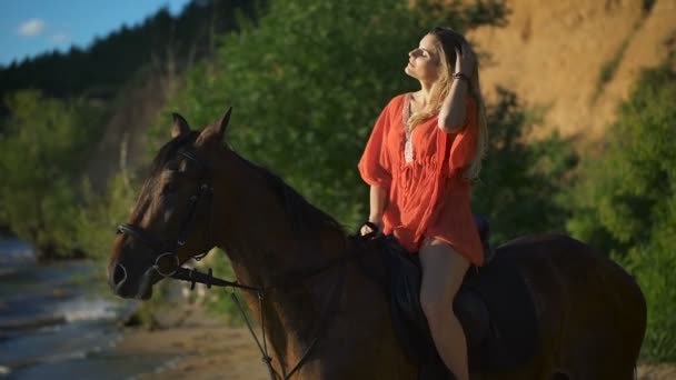 Una joven hermosa y sexy sentada en un caballo en una playa — Vídeo de stock