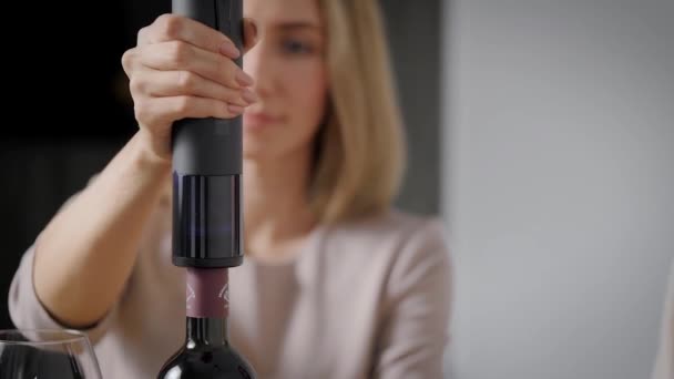 Una hermosa rubia abre el vino con un sacacorchos eléctrico. — Vídeo de stock