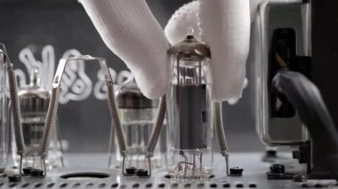 Tamirhanedeki bir mühendis eski radyo tüplerini değiştiriyor. El, amplifikatör panosundan vakum tüpünü çıkarır..