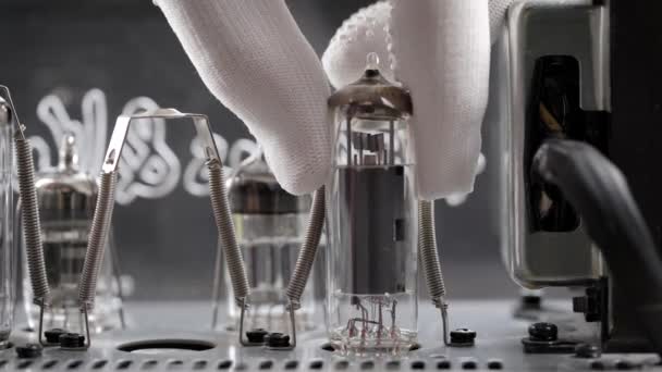 Ein Ingenieur in einer Reparaturwerkstatt ersetzt alte Funkröhren. Die Hand entfernt die Vakuumröhre von der Verstärkerplatine. — Stockvideo