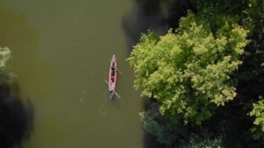 Bir hava manzarası. Amazon 'da birleşen bir kanoda iki kişi. Nehir ve kıyılar ağaçlarla kaplı..