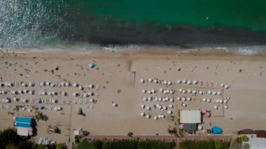Hava görüntüsü. Akdeniz sahil şeridinin en üst manzarası. Çerçevede, plajın güneşli ve şemsiyeli tatil yeri var..