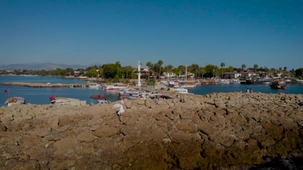 身穿白衣的瘦小女人走在石堤上.地中海沿岸的夏日. — 图库视频影像