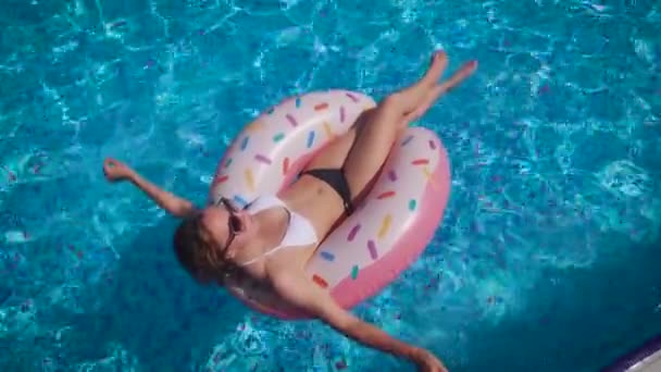 Привлекательная стройная женщина плавает по надувному кругу. Бассейн с чистой водой. — стоковое видео