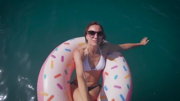 Wanita muda yang bahagia menikmati laut dan matahari. Wanita cantik berenang di atas cincin karet. — Stok Video
