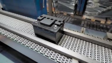 Araba aküleri montajı için otomatik hat. Siyah piller taşıma bandında hareket ediyor ve toplanıyor..