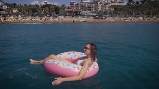 Glad ung kvinna njuta av havet och solen. Vacker kvinna simmar på en gummiring. — Stockvideo