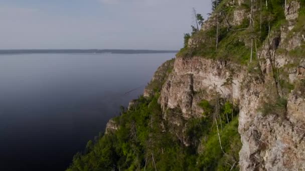 Vuelo a lo largo de un pintoresco acantilado sobre el río. Un enorme embalse y un empinado acantilado de piedra. — Vídeos de Stock