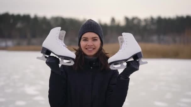 Mladá žena v tmavém saku přišla k zamrzlému jezeru na bruslení. V zimě může být příroda zábavná. — Stock video