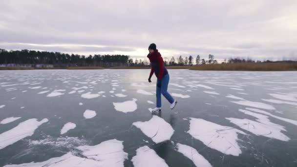 Una mujer joven y hermosa patina sobre hielo. El lago se congeló y se convirtió en una pista de hielo natural. — Vídeos de Stock