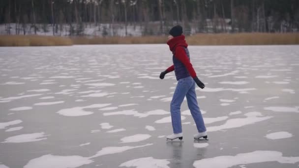 Mladá a krásná žena bruslí na ledě. Jezero zamrzlo a změnilo se v přírodní kluziště.. — Stock video