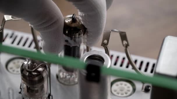 Een ingenieur in een reparatiewerkplaats vervangt oude radiobuizen. De hand verwijdert de vacuümbuis van het versterkerbord. — Stockvideo