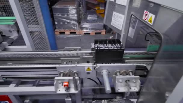 Línea automática para el montaje de baterías de coche. Las baterías negras se mueven y se acumulan en la cinta transportadora. — Vídeos de Stock