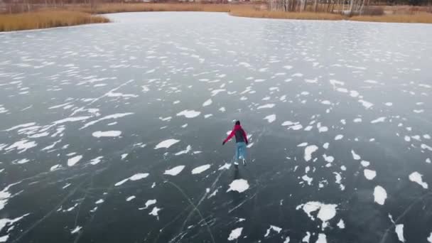 Vue aérienne. Amusement hivernal sur glace. Un beau cliché d'une hauteur, une femme monte sur des canyons sur un étang gelé. — Video