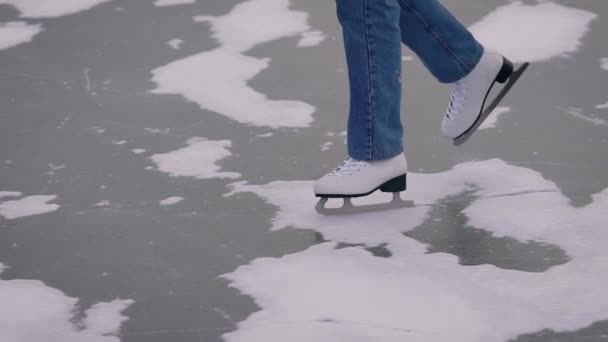 Ice skating on a frozen lake. In the frame, close-up of legs in jeans and white skates. — Stock Video