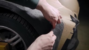 Arabaları ayarlıyorum. Bir adam plasticin kütlesinden bir parça oluşturur. Makinenin spor versiyonu için dış gövde kiti üretimi.